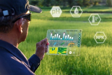 smart farming with iot, futuristic agriculture concept : farmer wears vr or ar glasses while monitoring rainfall, temeprature, humidity, soil ph with immersive experience on digital holographic screen