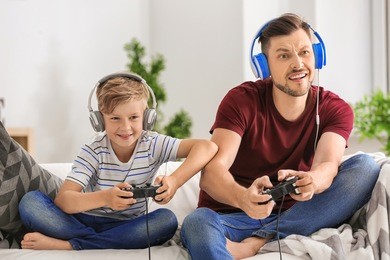 little boy and his dad playing video game together at home