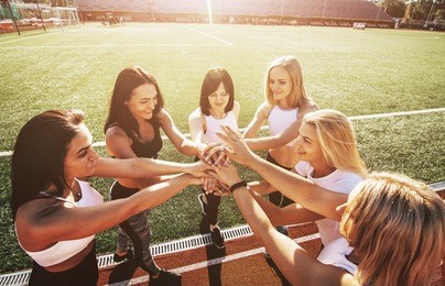 six women in the stadium putting hands. group of young sporty people celebrating giving friends a high five, raised hands, gesture of greeting, good-fellowship triumph