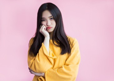 resentment, boredom, pouting lips. boring, dull face. offended girl looks with sadness and is ready to cry. pink background, yellow sweetshot, standing leaning on the arm