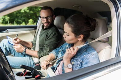 student fastening seat belt in car during driving test 