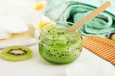 homemade skincare mask with fresh green mashed kiwi fruit in glass jar, close-up. natural organic beauty treatment for hair and body. 