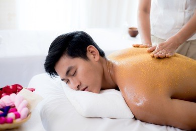 a handsome man getting a salt scrub treatment in spa salon