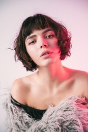young girl in a pink fur coat blue background studio red light