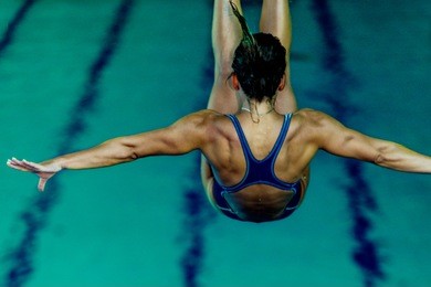 female diver jumping into the pool from diving board