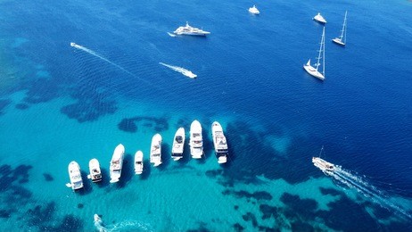 aerial photo of luxury yachts docked in tropical caribbean island with emerald clear sea