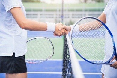 women tennis player handshaking after playing a tennis match. handshake at tennis court - agonism,respect,fair play,sport concept.