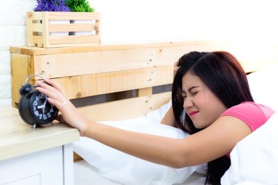 alarm clock is so loud and wakes beautiful woman up. attractive beautiful woman gets lazy for going to work on monday. pretty girl wakes up so late because lovely woman went to bed so late last night