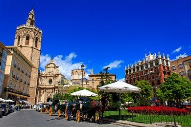 plaza de la reina - central place in valencia, spain. lively square surrounded by cafes, bars, shops and historic buildings, with a fountain and shaded benches.