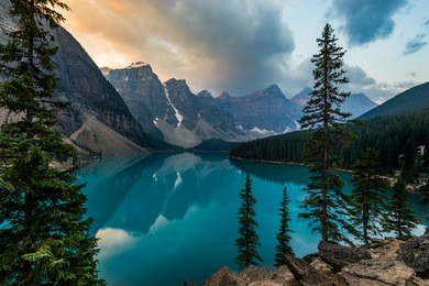 sunrise with turquoise waters of the moraine lake with sin lit rocky mountains in banff national park of canada in valley of the ten peaks.