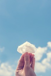 woman hand holding cotton wool on cloud sky background. the development of the imagination, copy space.