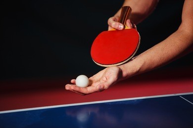 a young man is playing ping pong. he holds a ball and a racket in his hands