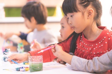 asian girl is drawing in kindergarten art classroom
