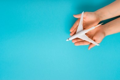 hand carefully holding model plane. airplane on blue color background. security concept
