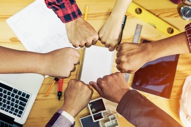teamwork and people concept - close up of international students hands making fist bump gesture. hands teamwork in meting room office.