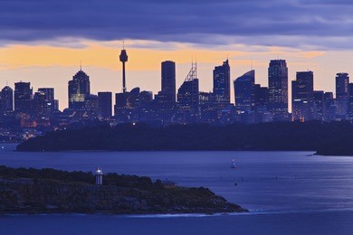 sydney city close-up view from north head over harbour and lighthouse at sunset with clouds over skyscrapers