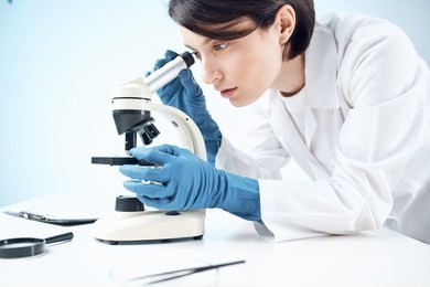   woman is looking through a microscope in a laboratory                             