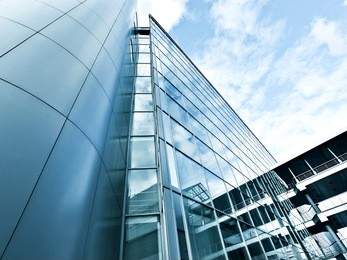 perspective and underside angle view to textured background of modern glass building skyscrapers over blue cloudy sky