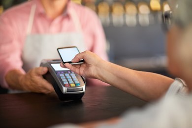 modern visitor paying through mobile payment system in smartphone after eating in cafe