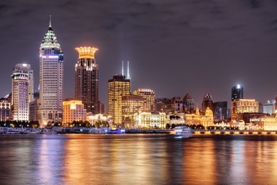 amazing night view of puxi skyline in shanghai, china. modern and old buildings of the bund (waitan) at historic center. colorful city lights reflected in water of the huangpu river.