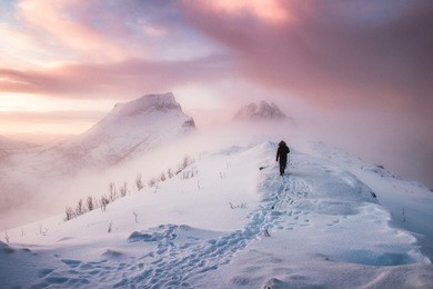 man mountaineer walking with snow footprint on snow peak ridge in blizzard at morning