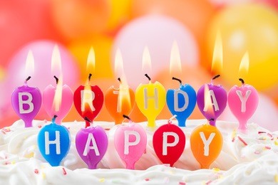 happy birthday written in lit candles on colorful background
