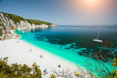 paradise beach with clear azure emerald sea water surrounded by high white rocky cliffs. fteri beach in kefalonia island, greece