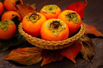 persimmon fruits and persimmon  leaves in basket on wooden background