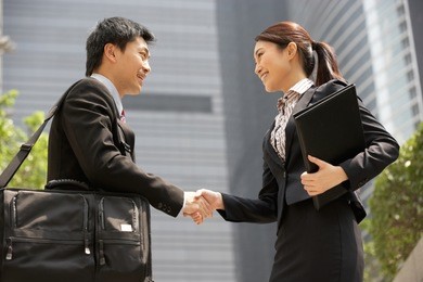 chinese businessman and businesswoman shaking hands outside office