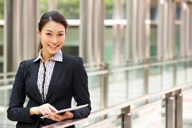 chinese businesswoman working on tablet computer outside office