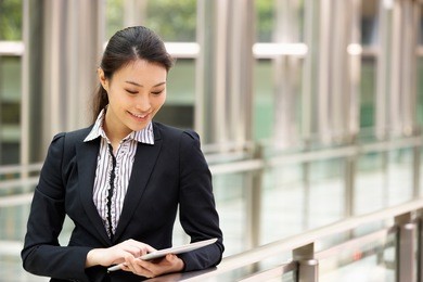 chinese businesswoman working on tablet computer outside office