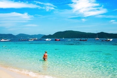 banana beach on coral (ko he) island on a sunny day, phuket, thailand. the woman goes to snorkeling.