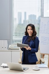 cheerful young asian business lady with tablet computer working in office