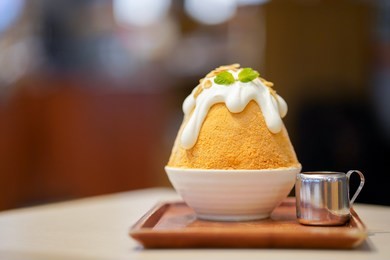closeup thai milk tea bingsu on tray, bingsu or bingsoo, korean shaved ice dessert with sweet toppings and fruit and varieties with ingredients, popular dessert.