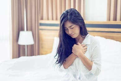 heart attack concept, asian business woman is unable to work, today so tired. she is sick serious and acute high heart rate attack in bed. young girl has problem of heart healthy