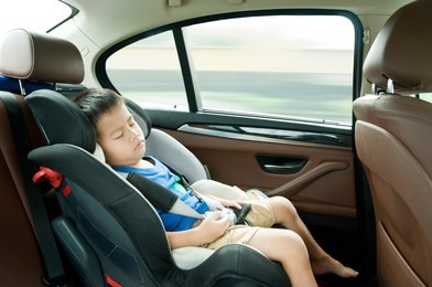 asian boy sleeping and sitting in a car seat while traveling