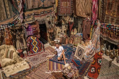young man tourist at an old traditional turkish carpet shop in cave house cappadocia, turkey kapadokya