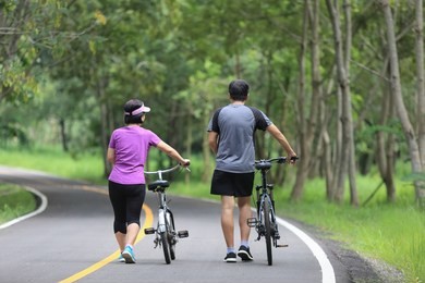 middle aged couple walking with their bicycle in park
