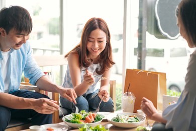cheerful multiracial friend smiling and eating healthy food in a restaurant, group of happy friend concept
