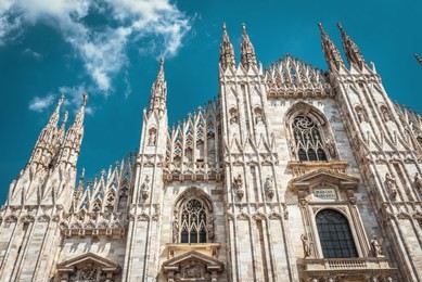 milan cathedral (duomo di milano), italy. it is a main landmark of milan. luxury facade of milan cathedral close-up. gothic decorations on the blue sky background. famous ornate architecture of milan.