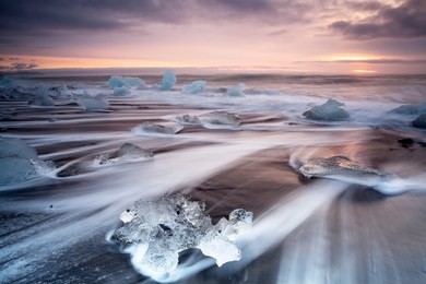 pieces of ice on the shore of jokulsarlon beach in iceland at sunrise. dramatic sky at sunrise on jokulsarlon beach in iceland. 
