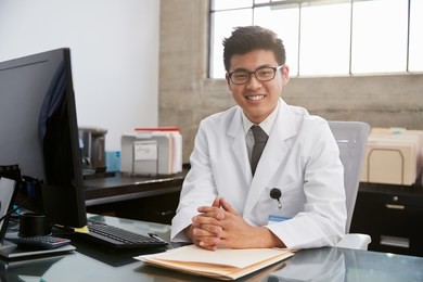 young asian male doctor sitting at desk, portrait