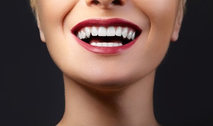close-up happy female smile with healthy white teeth, bright red gloss lips make-up. cosmetology, dentistry and beauty care. macro of woman's smiling mouth