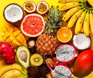 tropical exotic fruits assorted pineapple, coconut, pitahaya, kiwi, banana, mango, orange, avocado, passion fruit on yellow background