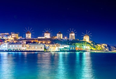 mykonos port with boats and windmills at evening, cyclades islands, greece