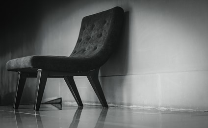 black classic chair with unique design in empty rest room near concrete wall on dark and dramatic background. depressed, sad and lonely concept. one empty armchair in living room. interior furniture.