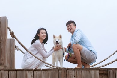 young asian couple on pier with pet dog.