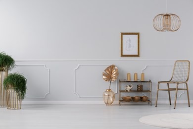 real photo of living room interior with fresh plants, poster on wall, gold chair and small rack with decor and candles