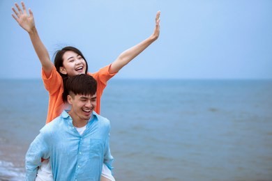 young asian couple playing at the seaside