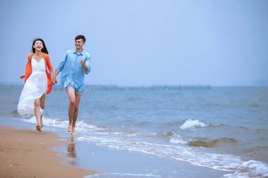 young asian couple playing at the seaside